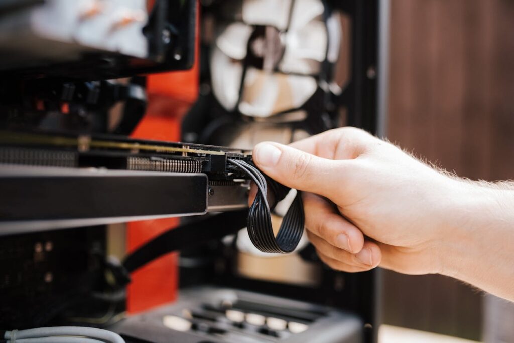 Close-up of a person’s hand connecting or adjusting a cable inside a computer case.